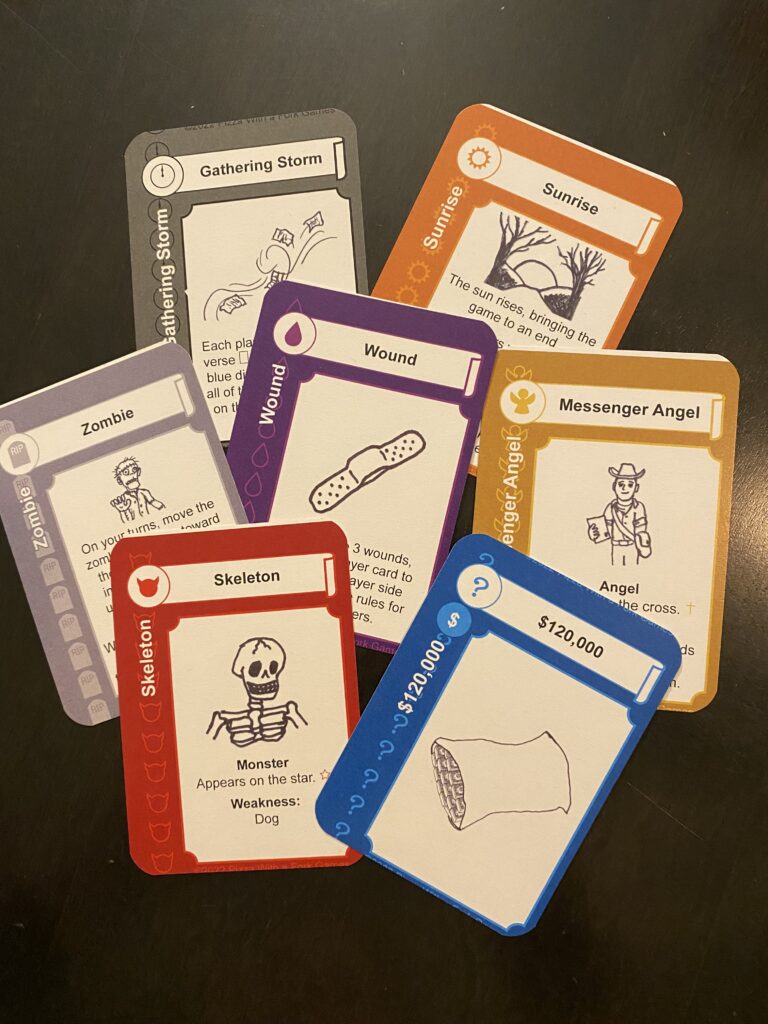 The fronts of the 7 colored cards for Haunted Inheritance: Red skeleton, blue pillowcase with $120,000, orange Sunrise, purple wound card with a picture of a band-aid, black Gathering Storm card, Gold Messenger Angel, and grey Zombie card