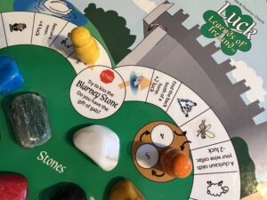 Blarney Stone Loop: polished stones on board with the yellow pawn close to the blarney space. The orange pawn is in the fairy mound space.