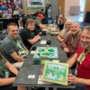 7 people sitting around the Luck: Legends of Ireland board game at a table